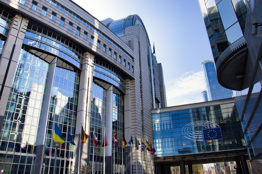 Modern european parliament building with flags and sky.