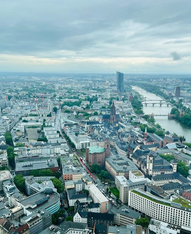 Factory with stockpiled goods and financial charts showing rising costs, symbolizing the cost of resilience in the global economy.