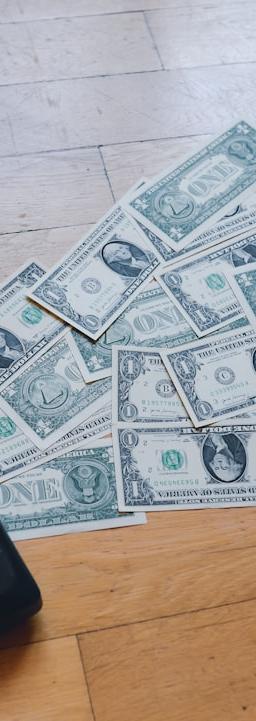 a pile of money sitting on top of a wooden floor