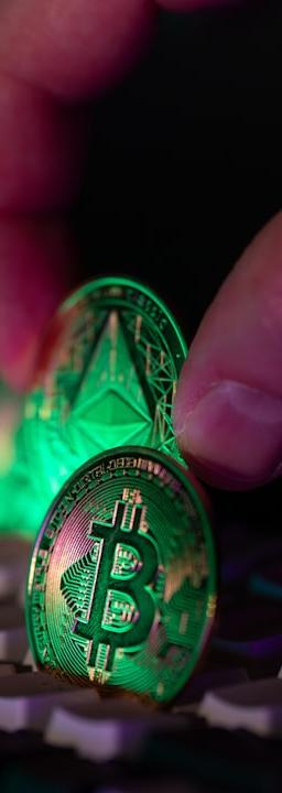 Hand placing glowing crypto coins on a keyboard.