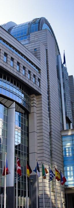 Modern european parliament building with flags and sky.