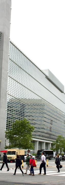 A group of people walking across a street next to tall buildings