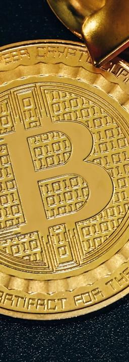 a gold bit coin with a red ribbon around it