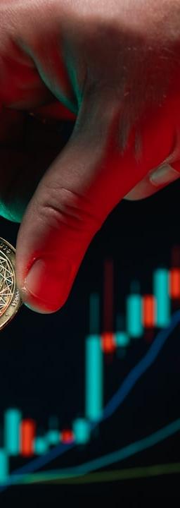 Hand holds ethereum coin over the stock chart.
