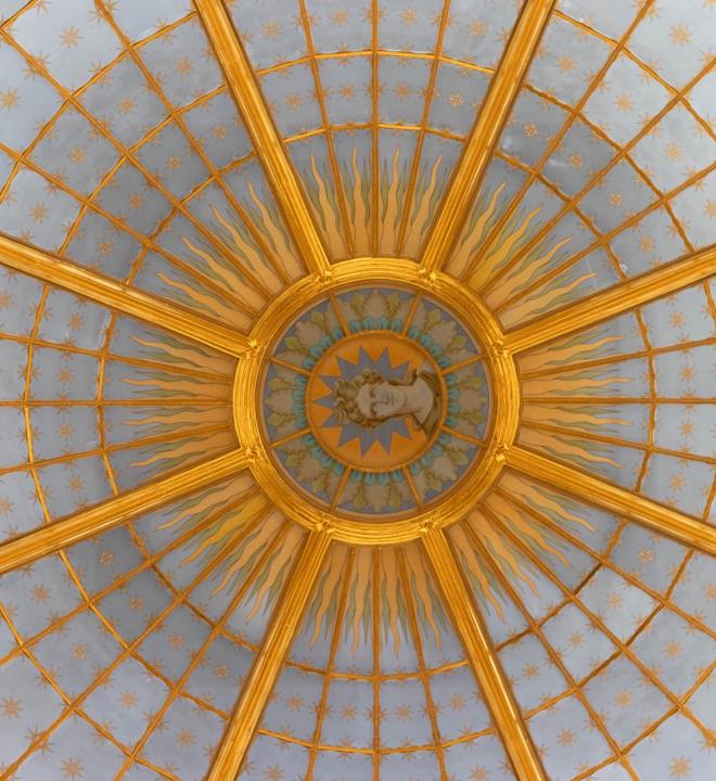 Ornate golden dome interior with radiating sunburst pattern.